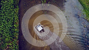 An off-road vehicle sails on the river. aerial above view top