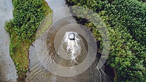 An off-road vehicle sails on the river. aerial above view top