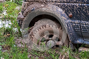 Off-road vehicle stuck in the mud. Dirty offroad car in swamp. Adventure travel concept. 4x4 SUV got bogged. Journey, tourism