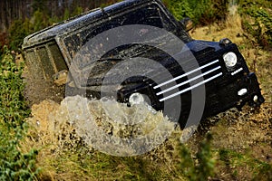 Off road vehicle or SUV crossing puddle with dirt splash. Competition, energy and motorsport concept. Car racing in