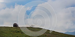 Off-road vehicle on top of a hill under a blue cloudy sky