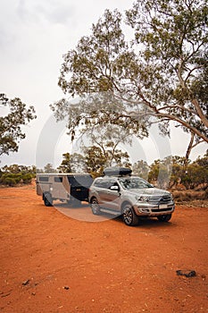 Off-road vehicle towing a camper through the Australian outback.