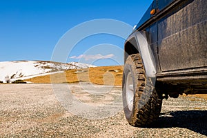 Off road 4x4 car in the snowy mountains on a sunny day. Off-road traveling, all terrain vehicle in nature