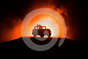 Off roader jeep silhouette on dark toned foggy sky background. Car with light at night.