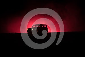 Off roader jeep silhouette on dark toned foggy sky background. Car with light at night.