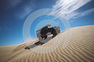 off-roader scaling daunting sand dune under clear blue sky