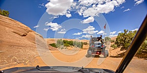 Off roading in Moab under blue sky with clouds