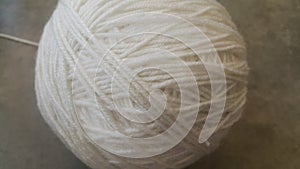 Off white ball of threads wool yarn for knitting on grey floor background