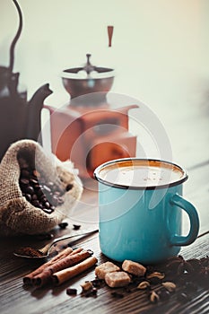 Ð¡offee in blue mug, sugar, coffee beans, spices and coffee mill on background.