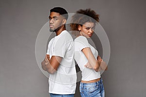 Offended african man and woman standing back to back with crossed hands