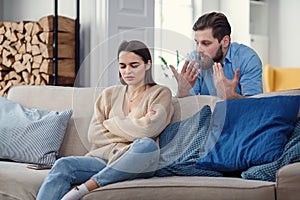 Offended angry woman sits on sofa at home after an argument with her husband. Broken marriage.