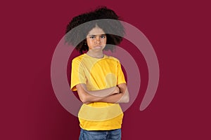 Offended black child posing over colorful studio background