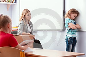 Offended child stands with his arms folded in the classroom