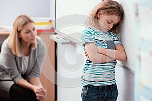 Offended child stands with his arms folded in the classroom