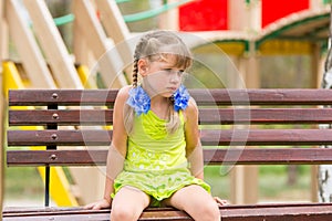 Offended five year old girl sitting on bench and crying