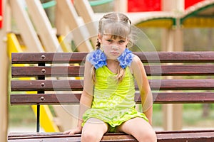 Offended five year old girl sitting on a bench at the playground