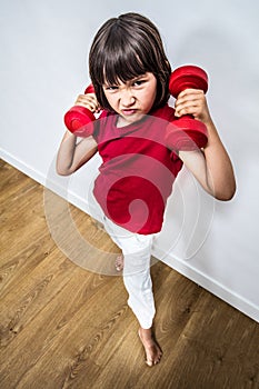 Offended frowning child expressing rage and violence with dumbbells