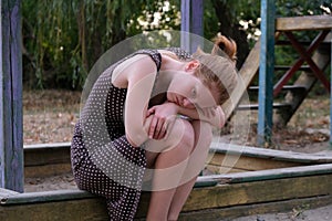 Offended girl sitting on a bench at playground