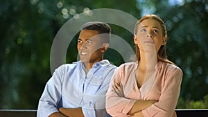 Offended girl sitting with folded hands, boy shocked with her whims, conflict