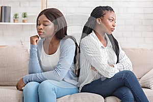 Offended girlfriends sitting back to back, ignoring each other after quarrel