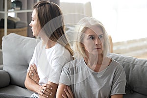 Offended mother and daughter sit aside avoiding talking