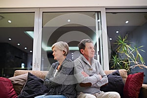 Offended senior couple sitting on a couch with arms crossed