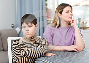 Offended son sitting at tablr after quarrel with mother at home