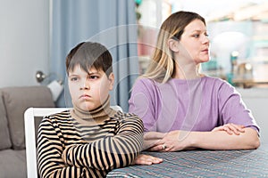 Offended son sitting at tablr after quarrel with mother at home