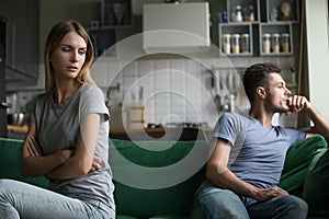 Offended upset man and woman sitting separately on couch