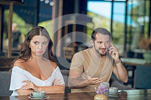 Offended woman and inattentive man talking on smartphone