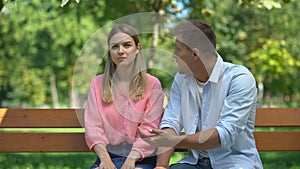 Offended woman listening guilty boyfriend explanations at park after quarrel