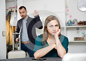 Offended woman at table on background with man leaving her