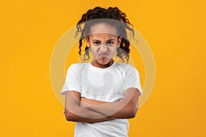 Offended young black girl standing with folded arms
