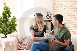 Offended young woman refusing to take gift from her boyfriend at home