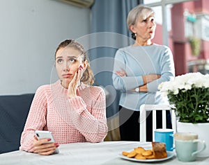 Offended young woman sitting at table after quarrel with mother