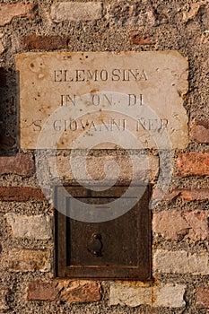 Offering box slot outside old church in Italy.