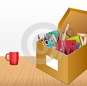 Office accessories in a cardboard box on wooden background