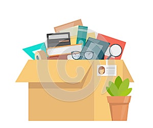 Office accessories in cardboard box. Working stuff, documents, plant, photo frame, calculator, glasses. Moving into a new office.