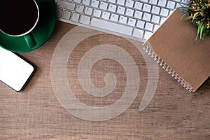 Office accessories laptop, smartphone, notepad, and coffee cup on a wooden table background.
