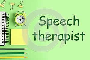 Office accessorises and text Speech therapist on green background, flat lay