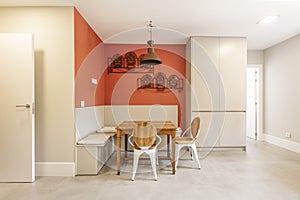 Office area of a kitchen in an apartment with gray tones in the furniture and a square wooden table and a bench to sit in the