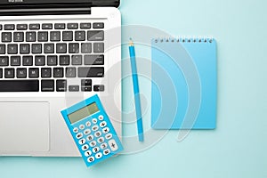 Office blue desk table with laptop computer, notebook, pencil, calculator. Top view with copy space