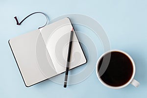 Office blue table with blank notepad, pencil and white cup of coffee. Copy space for text. Flat lay. Top view.