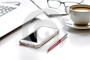 Office breakfast with coffee, phone and laptop on white desk photo