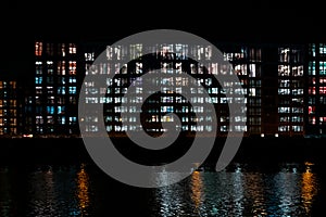 Office building facade at night, illuminated windows of corporate building