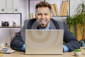 Office businessman hiding behind laptop computer making funny silly face fooling around, disrespect