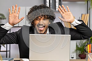 Office businessman hiding behind laptop computer making funny silly face fooling around, disrespect