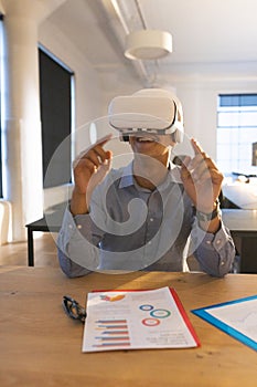In office, businessman using VR headset interacting with virtual presentation documents