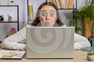 Office businesswoman hiding behind laptop computer making funny silly face fooling around disrespect