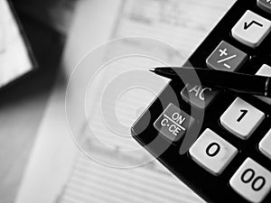 Office calculator and a pen over documents close up shot in black and white